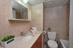 A bathroom with a sink, mirror, toilet, and bathtub. - Family Vacation by Kinneret All Comforts (Tiberias)