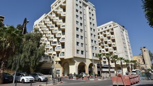 A multi-story residential building with balconies, a gated entrance, and a parking area with cars. - Family Vacation by Kinneret All Comforts (Tiberias)