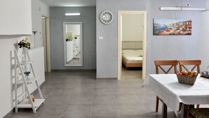 A room with a bed, a dining table with chairs, a clock, and a painting on the wall. - Luxury Suite with Jaccuzzi & Pool (Tiberias)