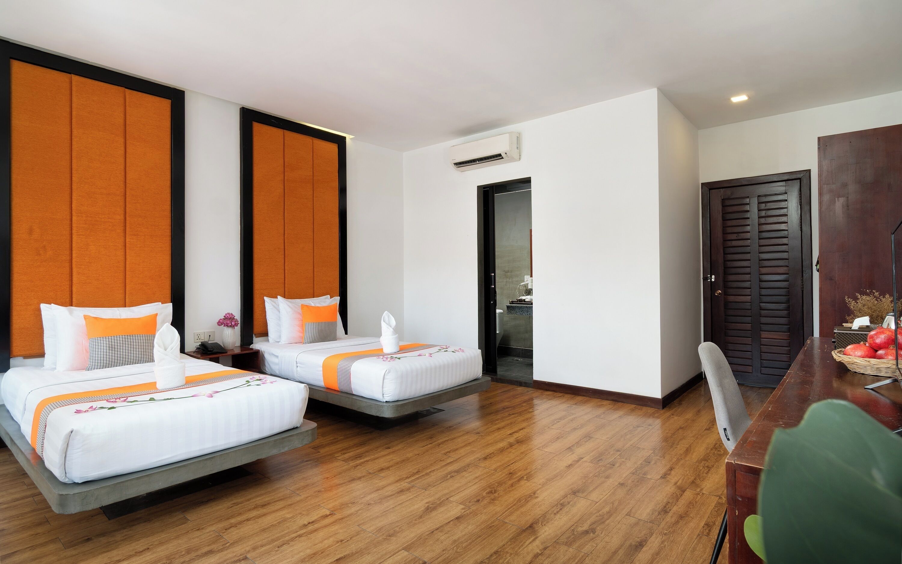 Habitación de hotel con dos camas, piso de madera, un escritorio y un armario.