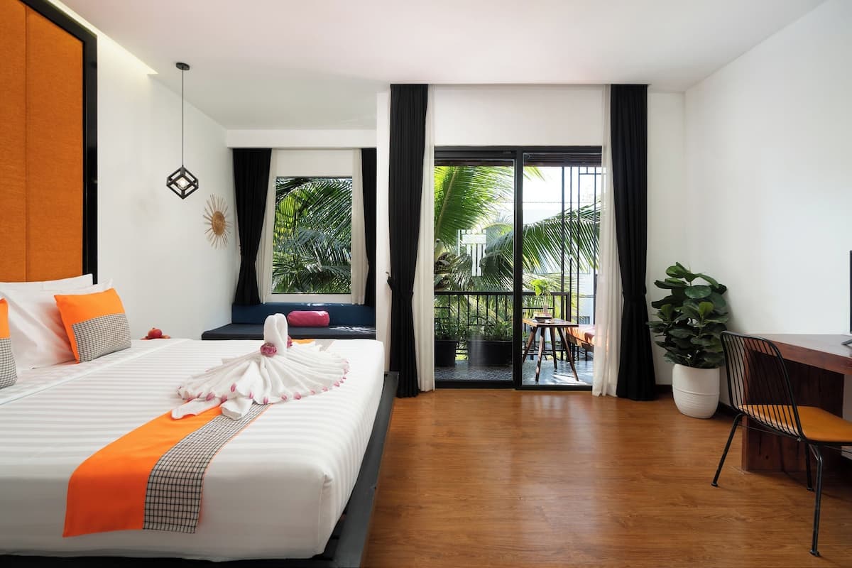 A hotel room with a large bed, a desk, a chair, and a view of the outdoors.