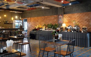 Interior de restaurante con paredes de ladrillo, una zona de bar y un espacio para bufé.
