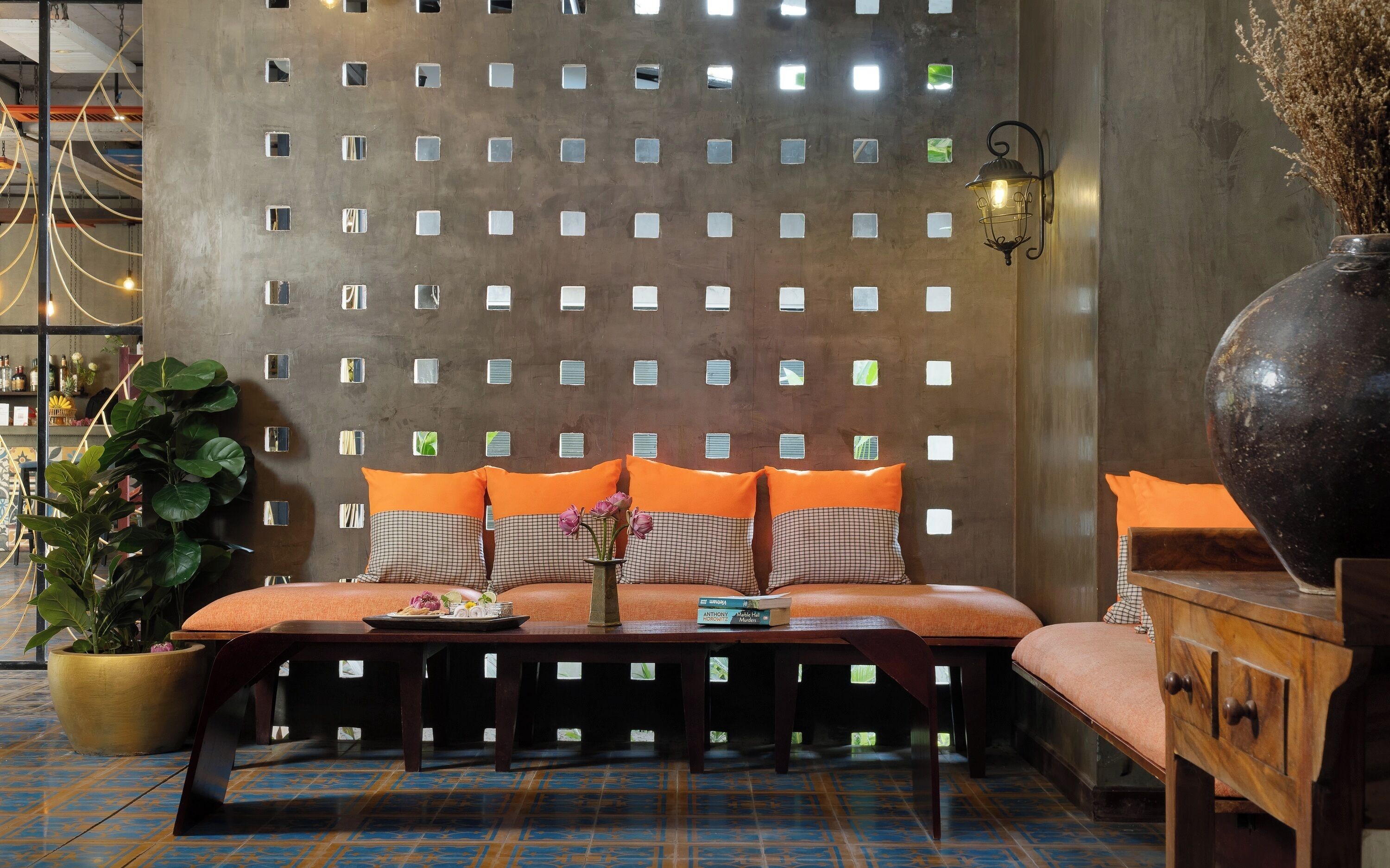 A room with a checkered sofa, a wooden table, and a decorative wall with square cutouts.