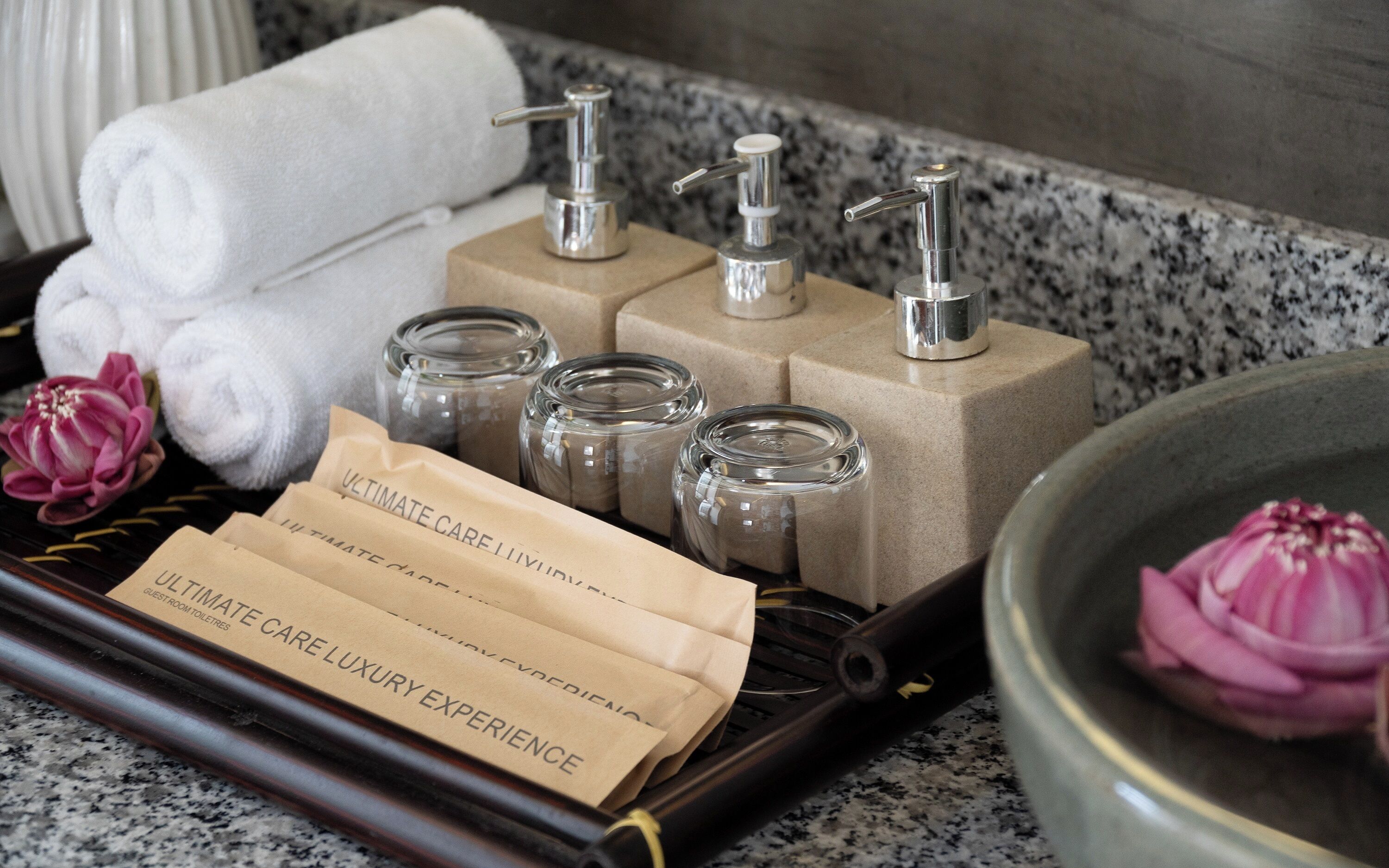 Un plateau contenant des articles de toilette, des serviettes et une fleur.
