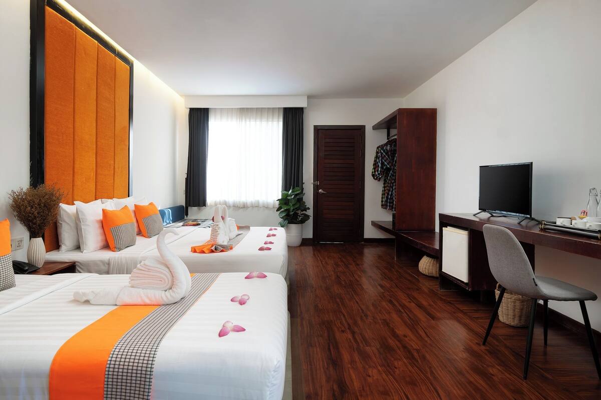A hotel room with two beds, a desk, a TV, and a wardrobe.