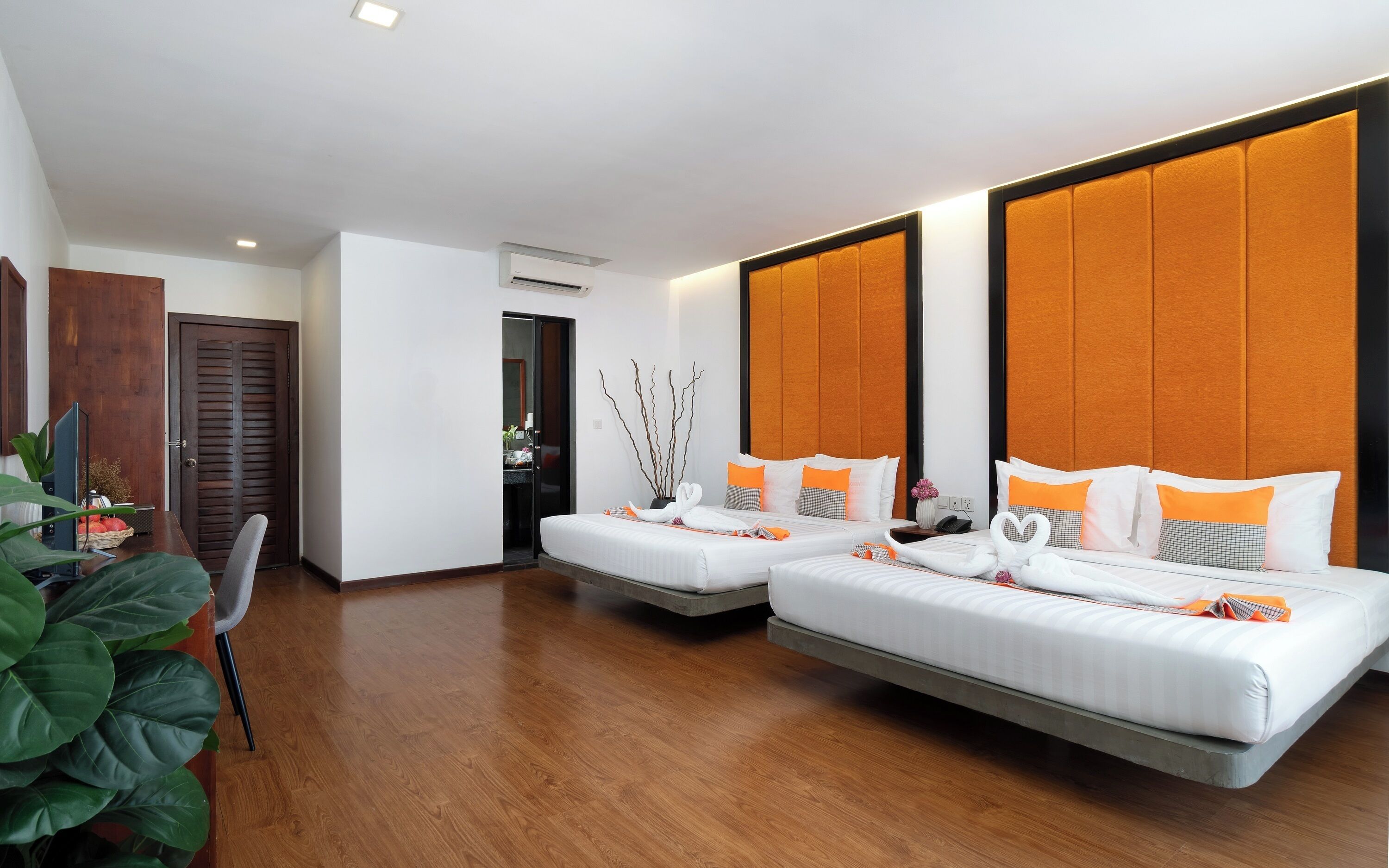 A modern hotel room with two beds, a wooden floor, and a large window.
