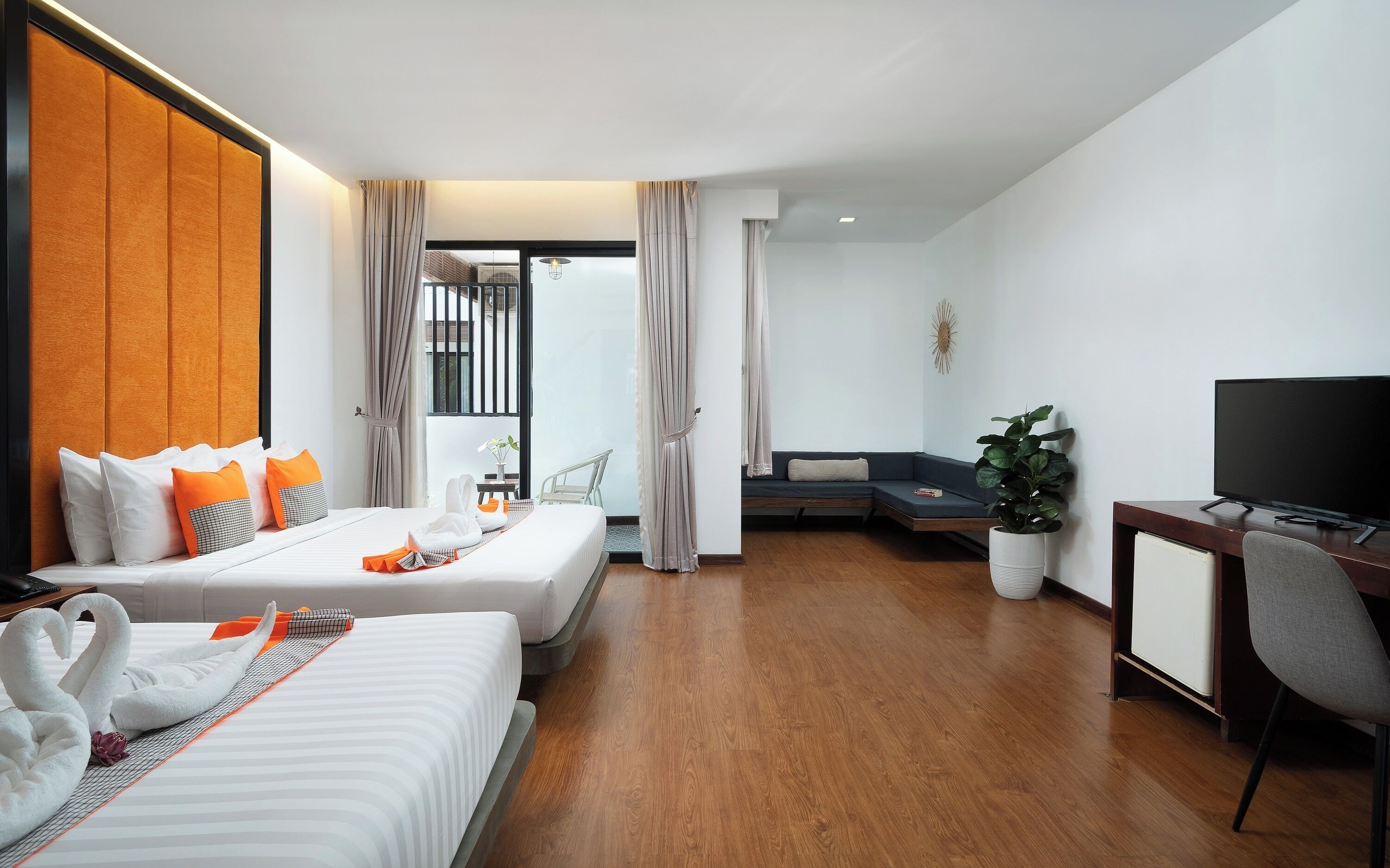 Una habitación de hotel con dos camas, un escritorio, un televisor y una planta en maceta.