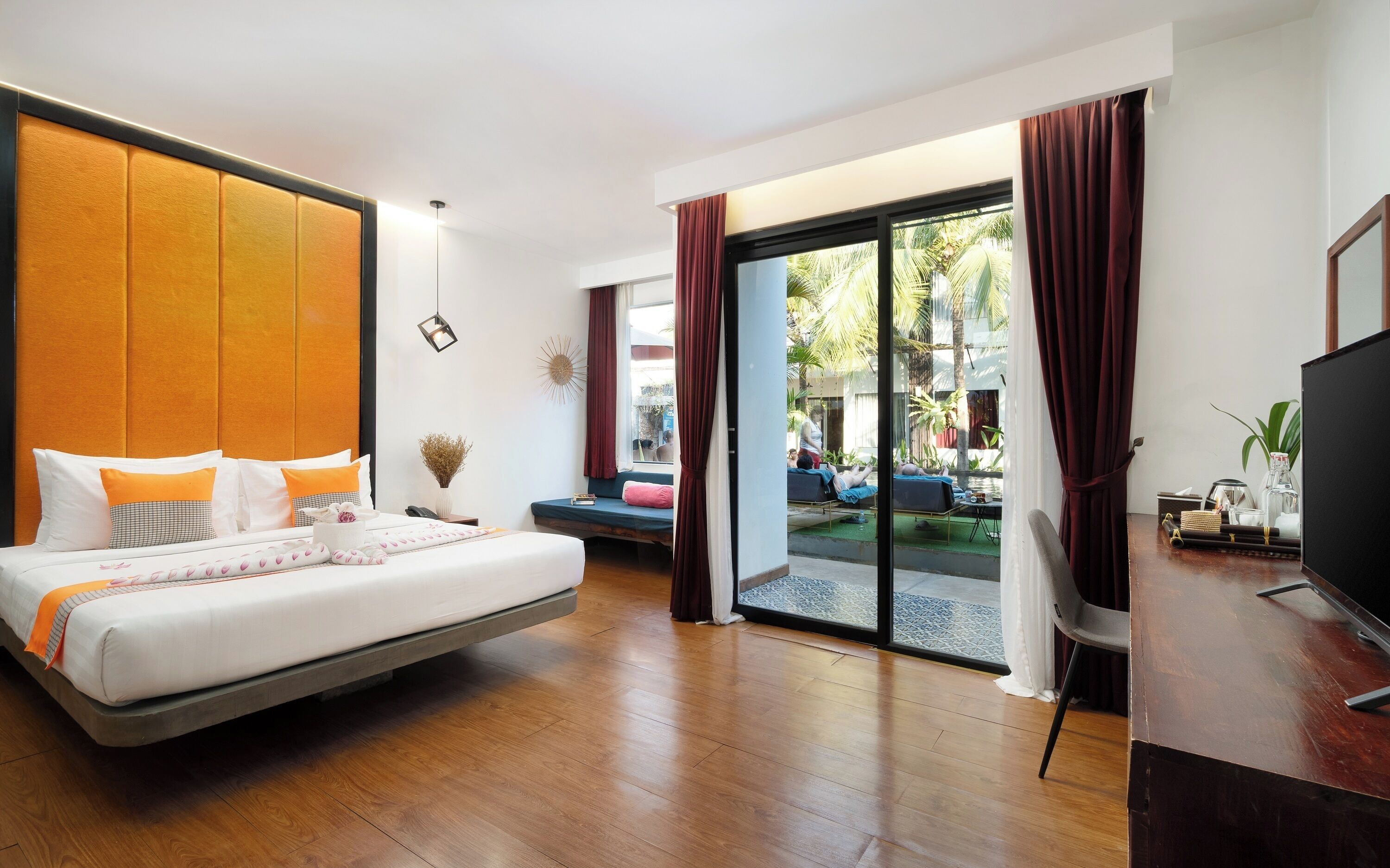 A modern hotel room with a large bed, a desk, and a view of the outdoor area.