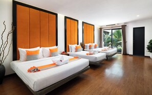 Habitación de hotel con tres camas, cada una con ropa blanca y detalles naranja, ventanas amplias y vista a zonas verdes.