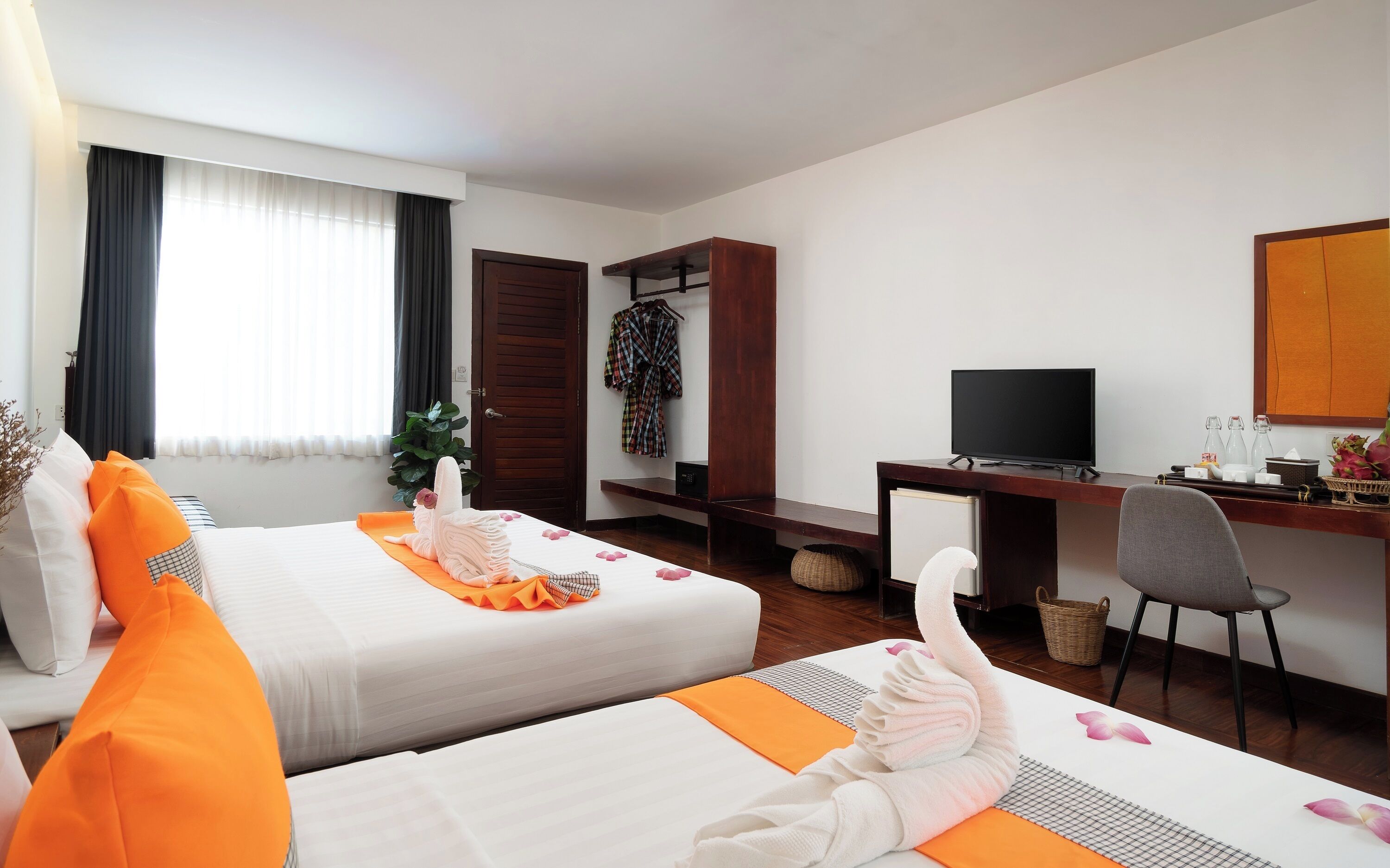 Een hotelkamer met twee bedden, een bureau, een stoel, een televisie en een kledingkast.