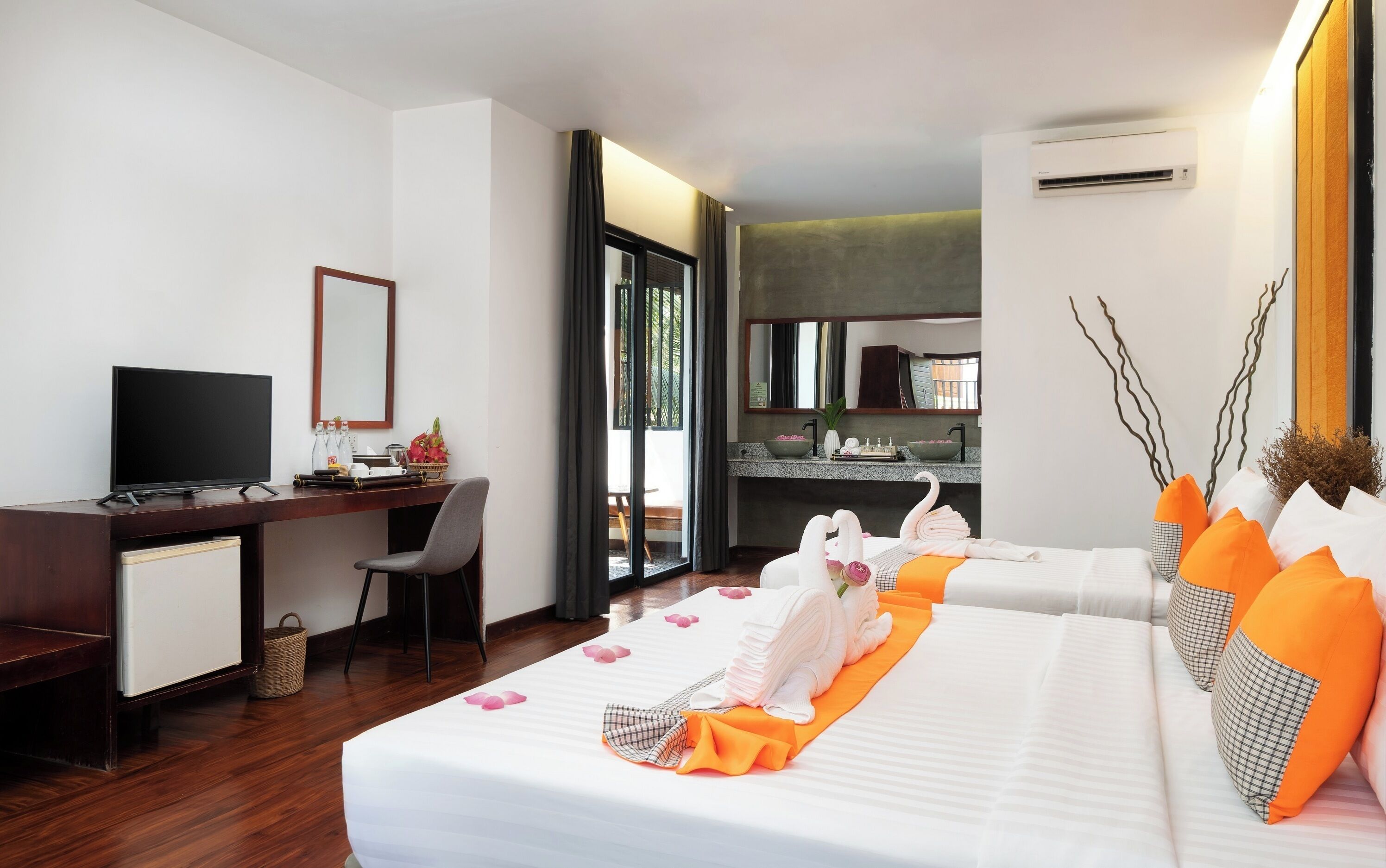A hotel room with a bed, a desk, a television, and a bathroom visible through an open door.