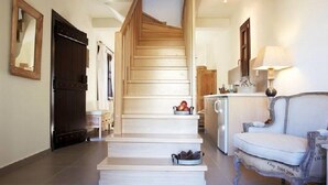 Una escalera conduce a un segundo piso, un área de cocina con pileta y armarios, y un sofá blanco de diseño vintage.