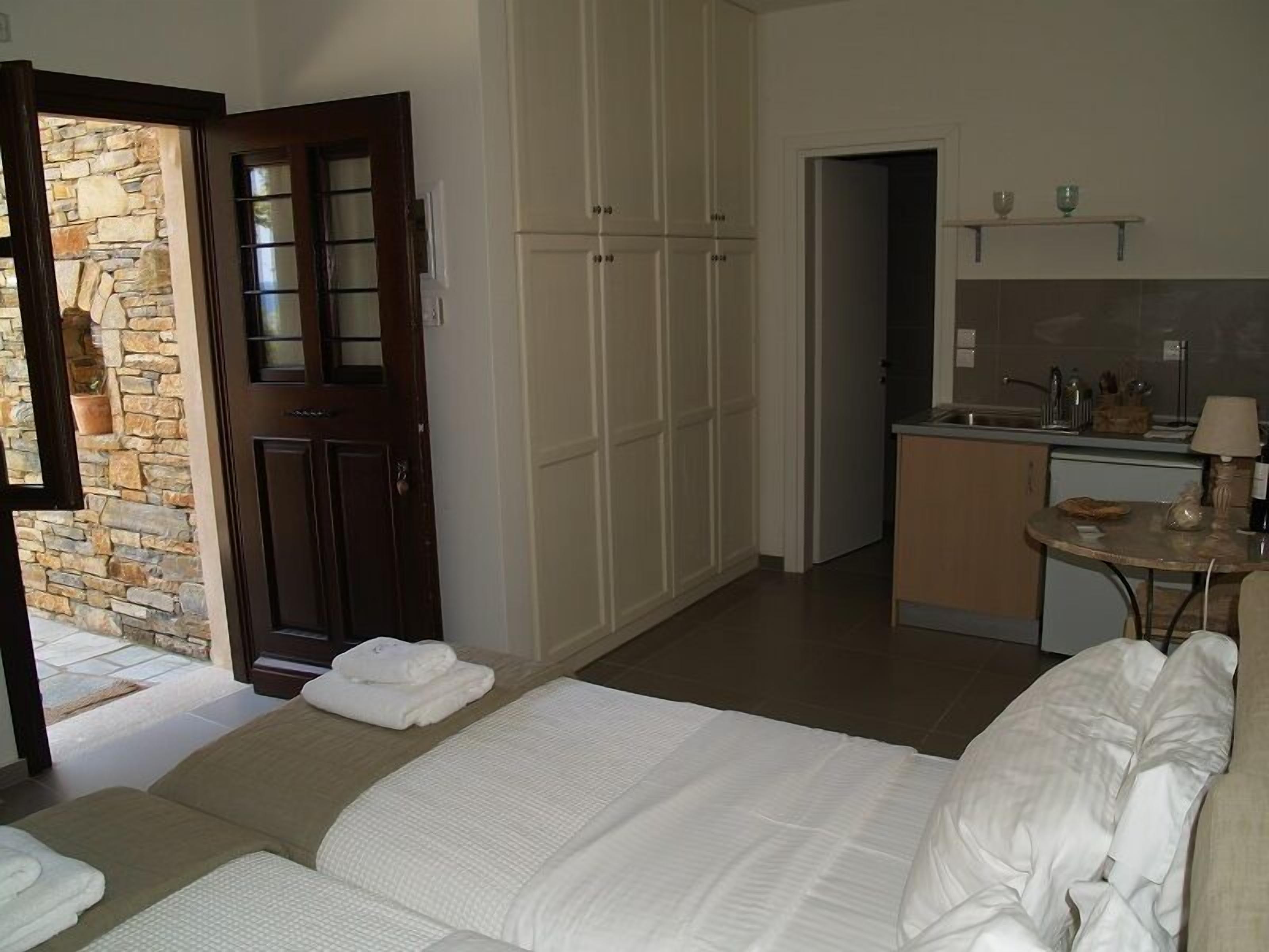 A bedroom with a bed, a bathroom with a shower, and a kitchenette.