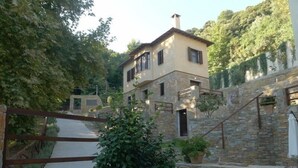 Una casa de dos pisos de piedra con una escalera de piedra que lleva a la entrada.