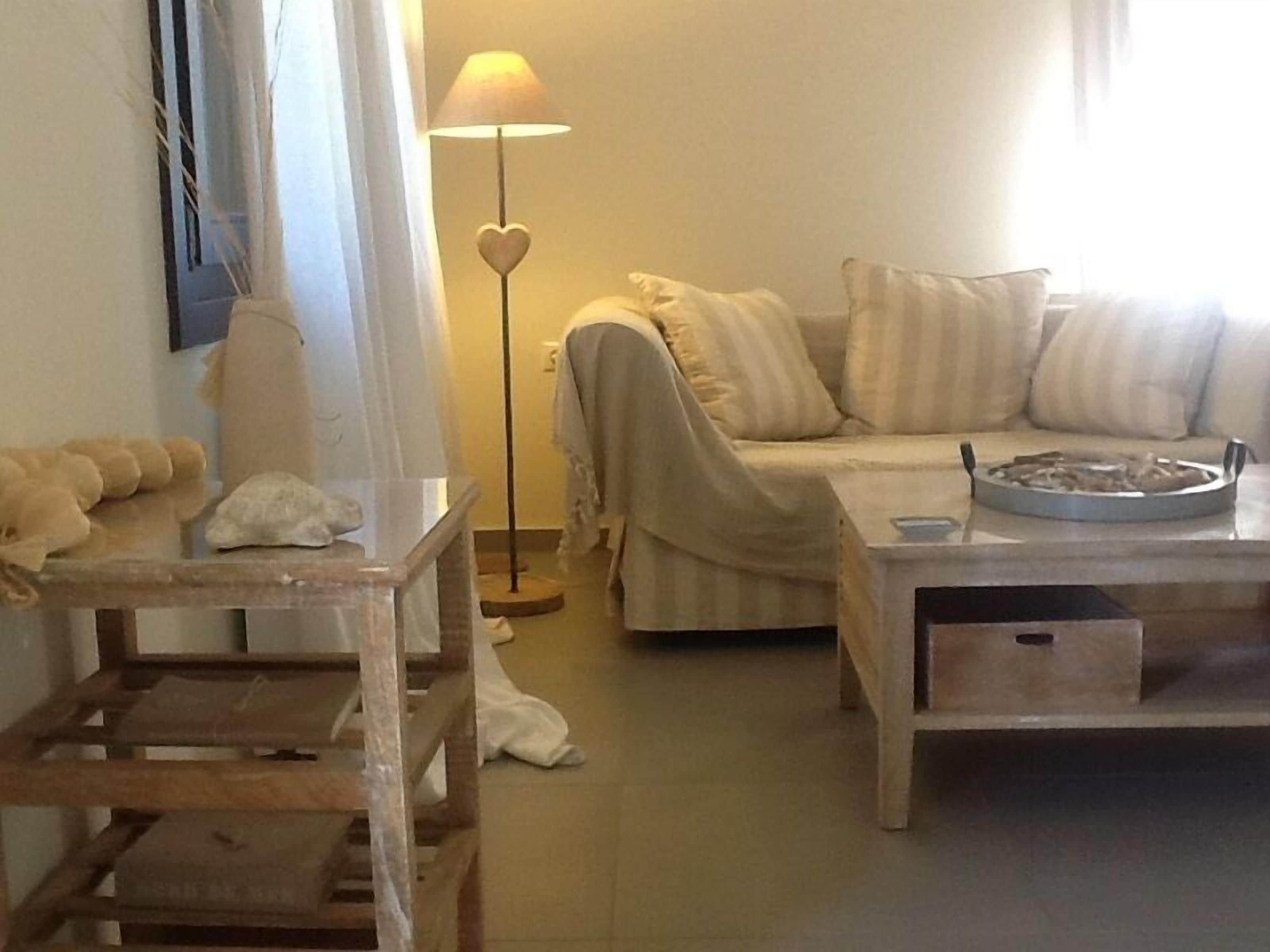 A cozy living room with a sofa, a coffee table, a lamp, and a small table with a decorative item.