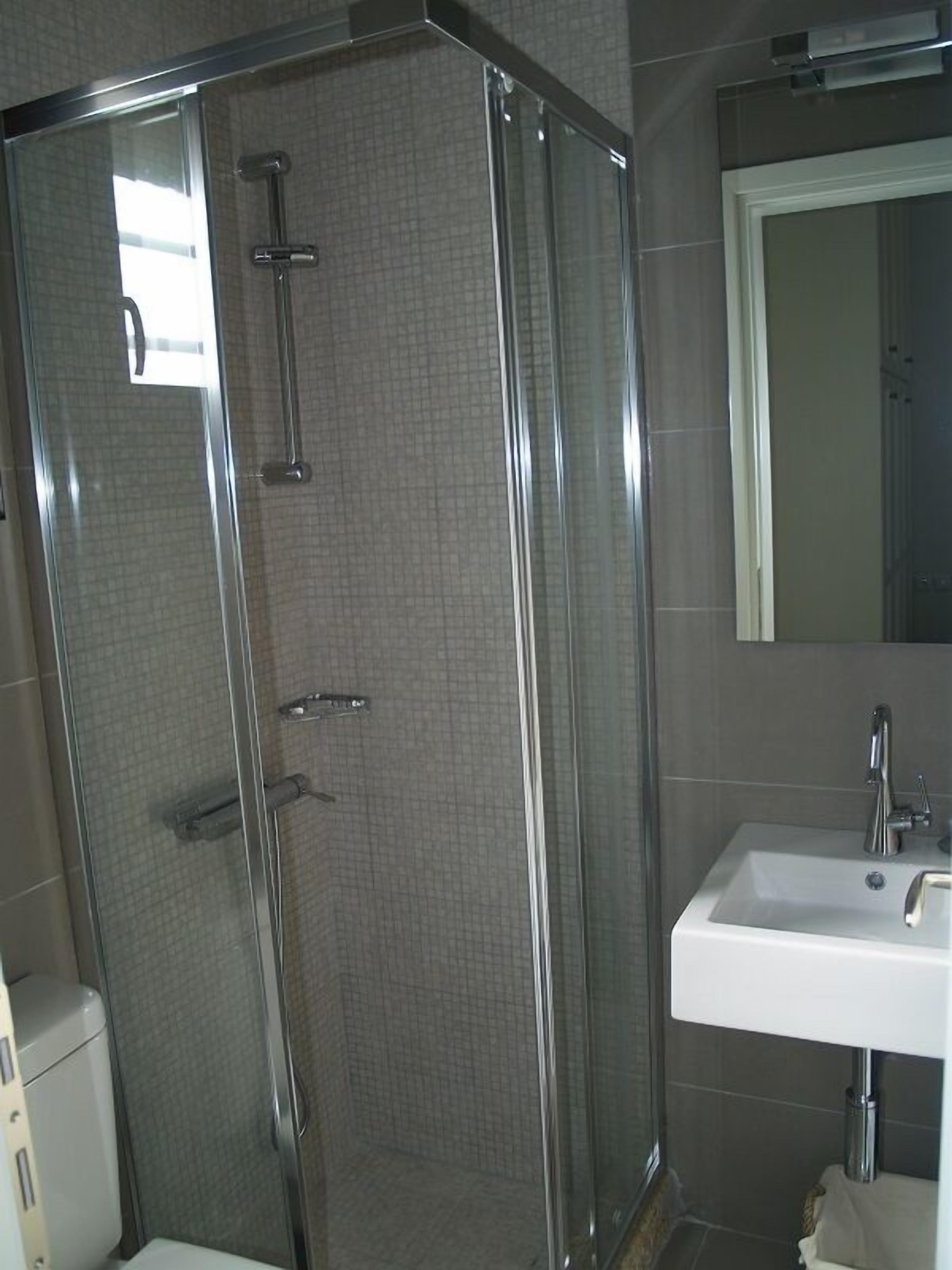A modern bathroom with a glass-enclosed shower, a white sink, and a mirror above the sink.