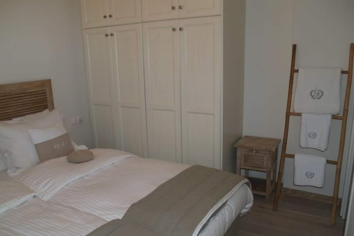 Un dormitorio con cama, armario y una escalera de madera con toallas.