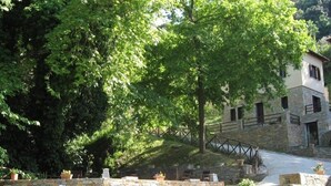 Una escalera de piedra conduce a un edificio de piedra con un puente de madera sobre un pequeño arroyo.
