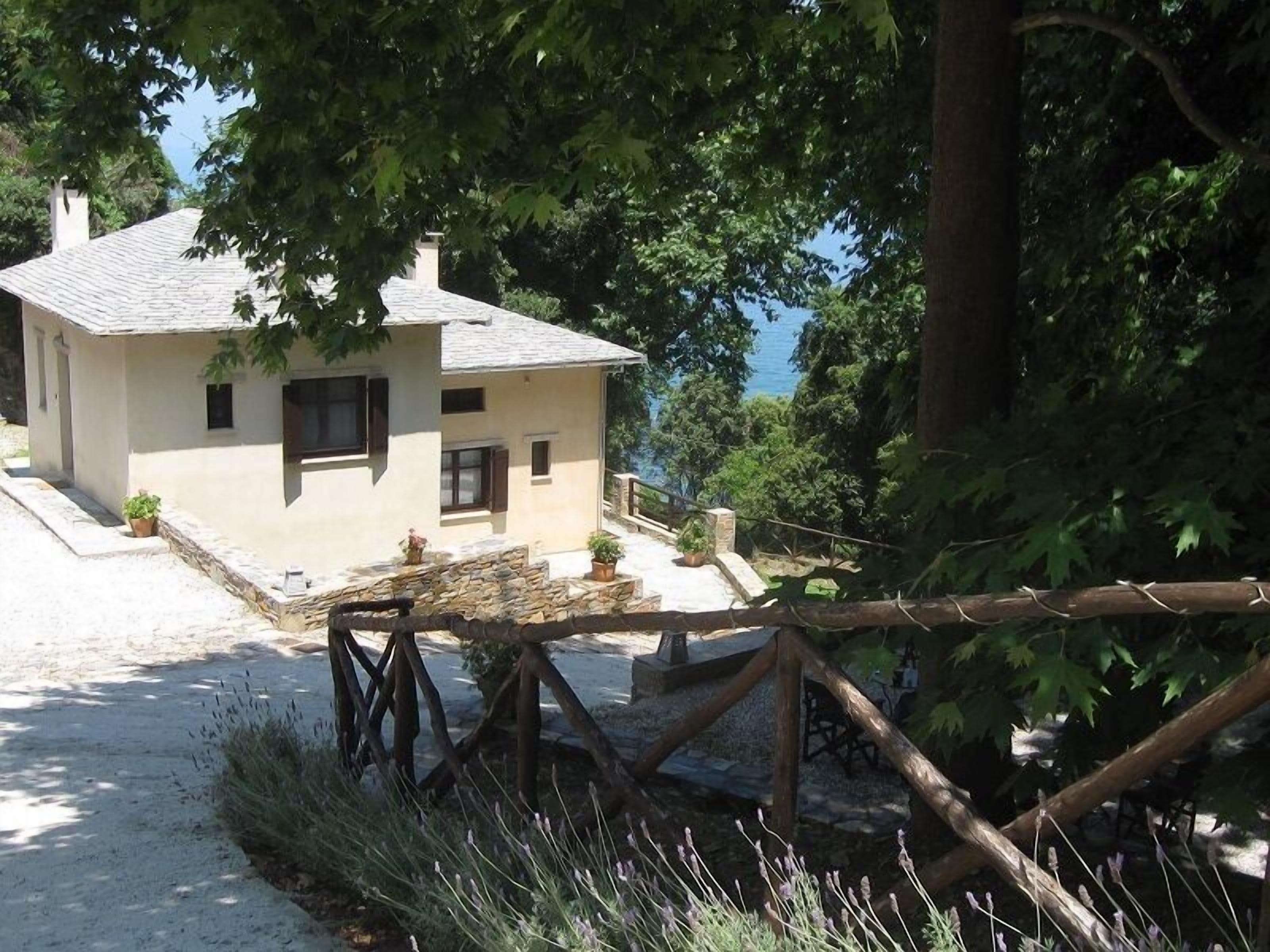 A two-story building with a stone facade, a small porch, and a view of the sea.