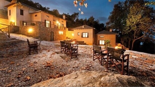 Un edificio de piedra con un patio, mobiliario exterior e iluminación en la entrada.
