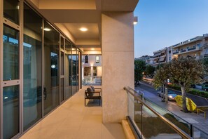 A modern building with large glass windows, a bench, and a railing overlooking a street.