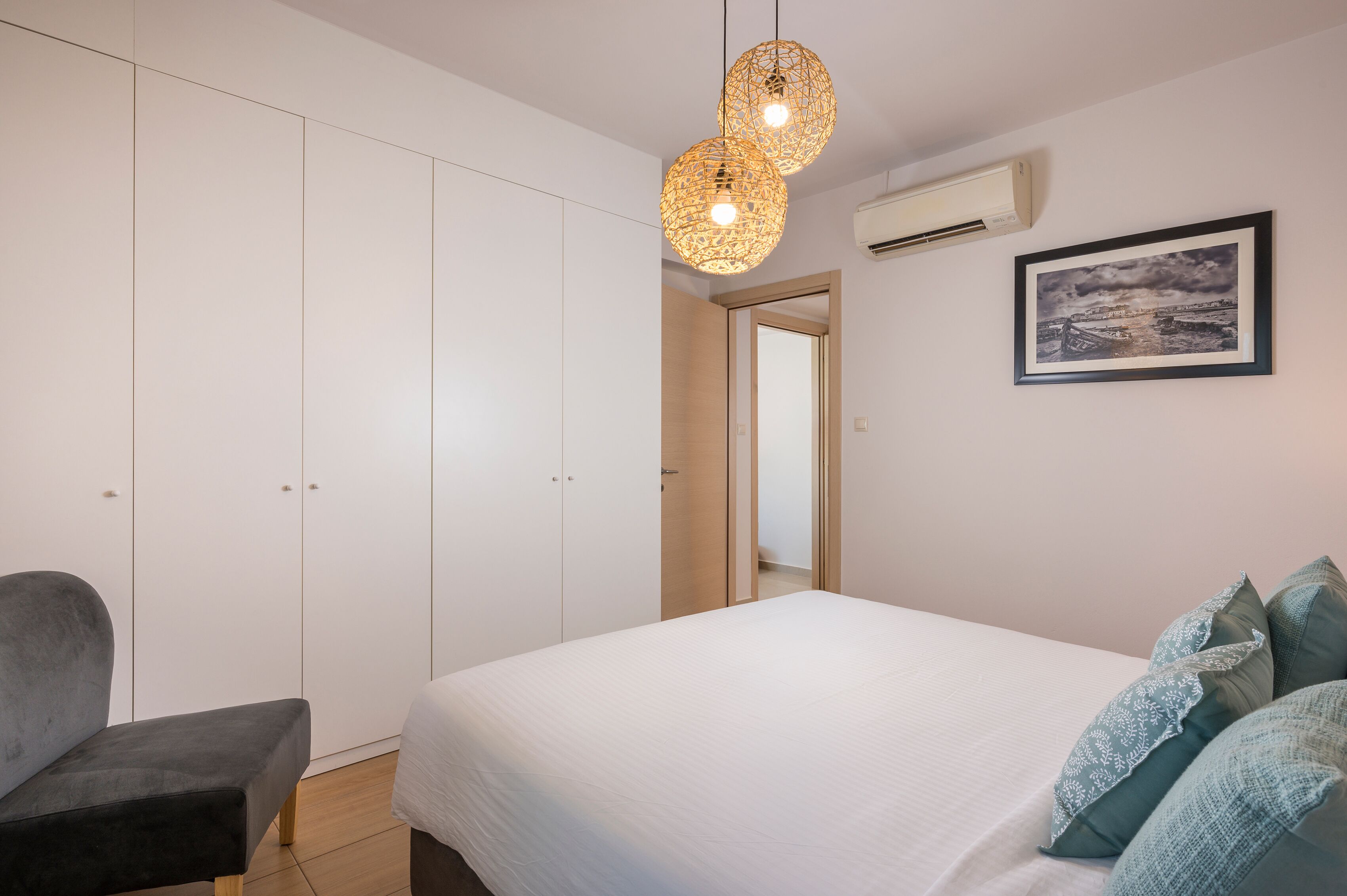 A bedroom with a bed, a chair, a wardrobe, and a hanging light fixture.