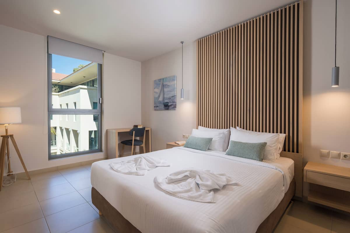 Una habitación de hotel moderna con una cama grande, un escritorio y una ventana con vistas a edificios.