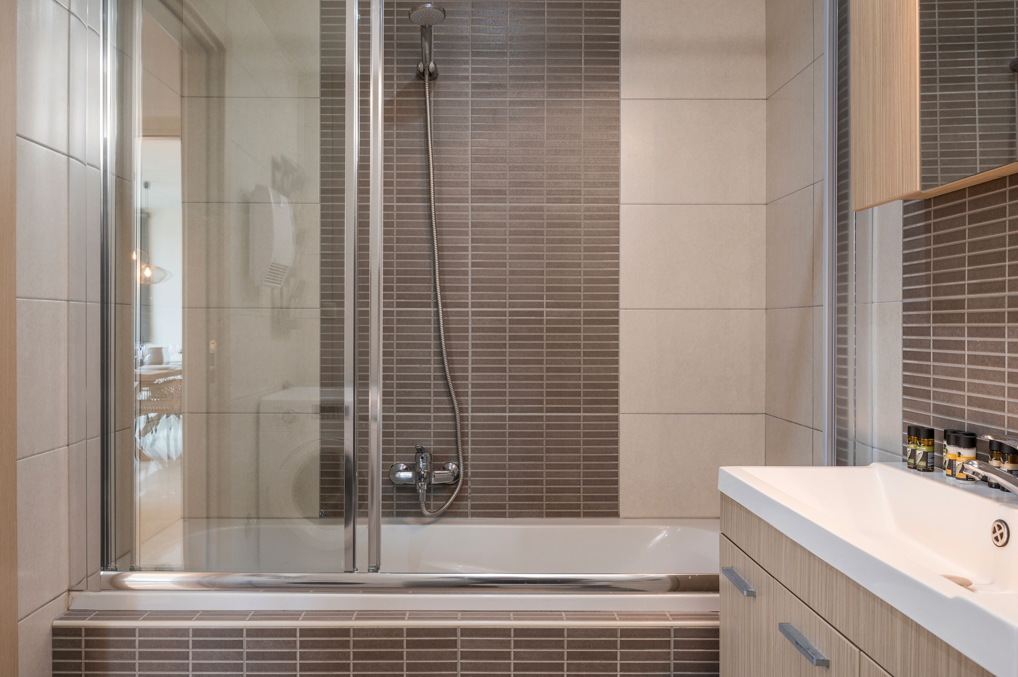 Un baño moderno con ducha envuelta en vidrio, una bañera y un tocador con espejo.