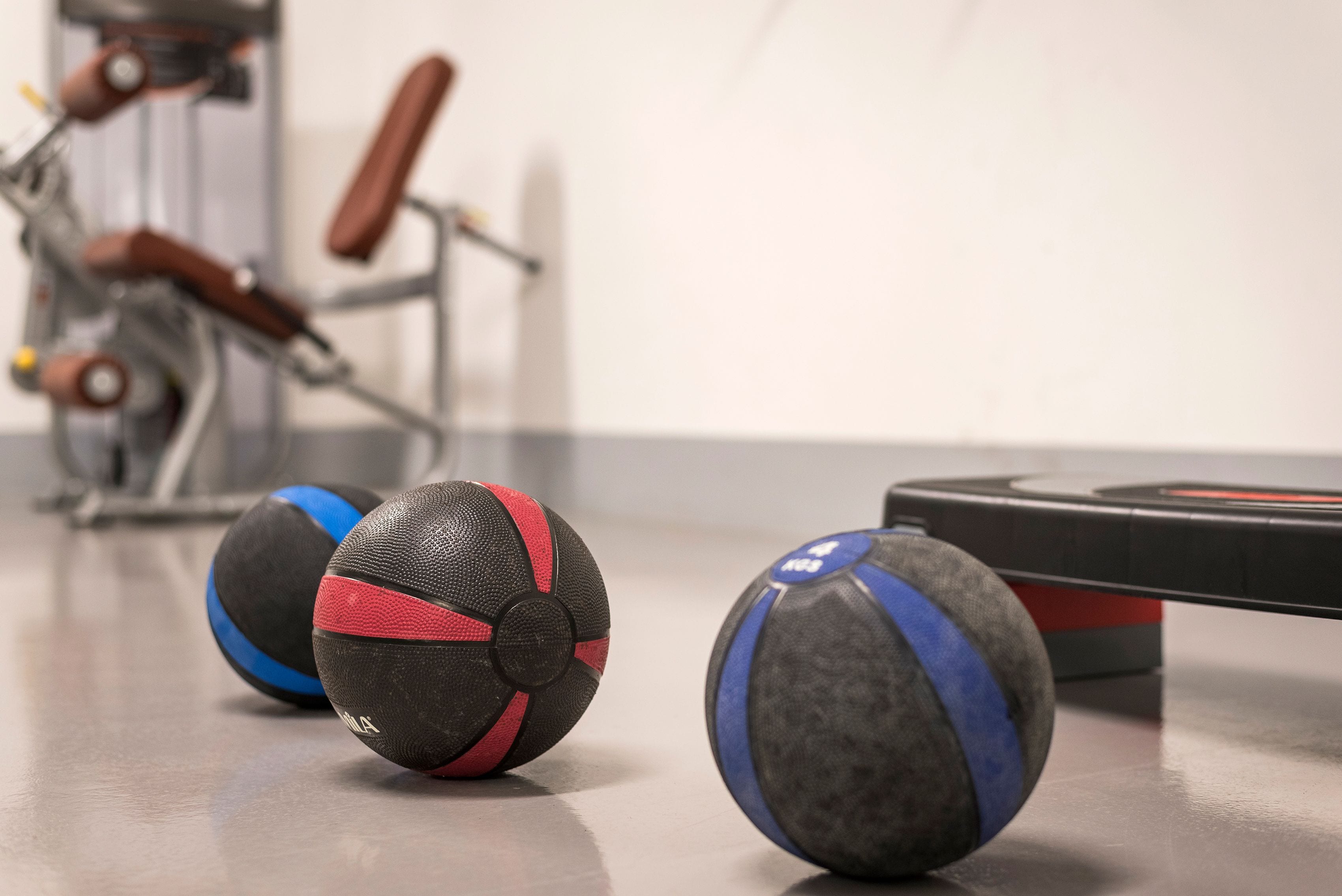 Exercise equipment, including a stationary bike and a rowing machine, in a gym setting.