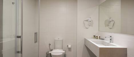 A modern bathroom with a glass shower enclosure, a white sink with a beige countertop, and a large mirror above the sink.