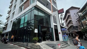 A modern hotel with multiple floors, large glass windows, and a visible entrance. - Coco Boutique Hotel (Patong)