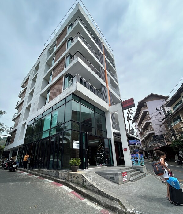 A modern hotel with multiple floors, large glass windows, and a visible entrance. - Coco Boutique Hotel (Patong)