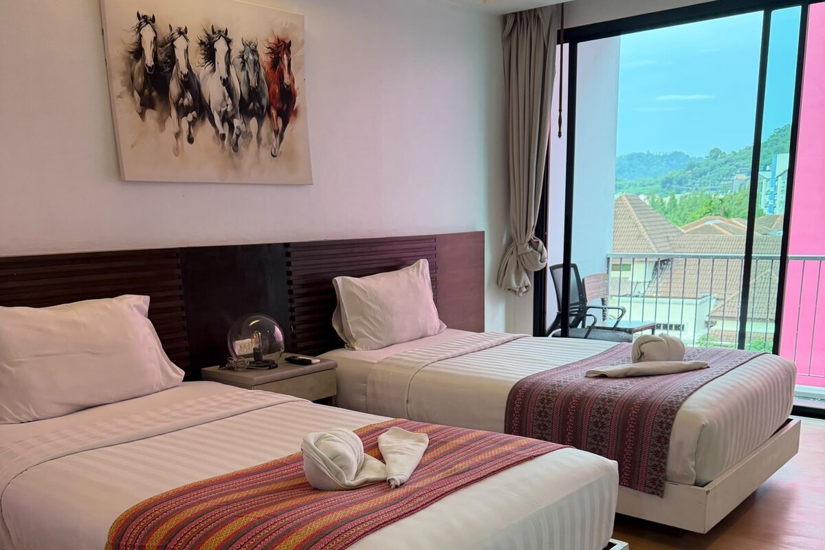 Habitación de hotel con dos camas, un cuadro en la pared y un balcón con vistas.