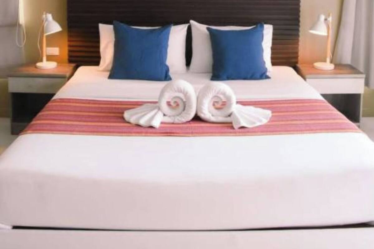 A hotel room with a large bed, two nightstands, a dark headboard, and a striped bedspread.