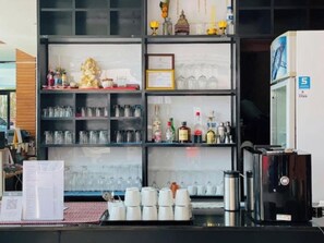 A bar area with shelves of glasses, bottles, and a coffee machine.