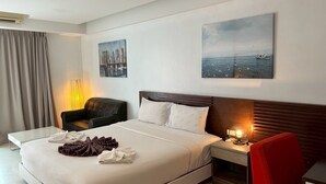 A modern hotel room with a large bed, a chair, a desk, and artwork on the walls. - Coco Boutique Hotel (Patong)
