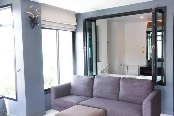 A modern room with a grey sofa, a large mirror, and a deer head decoration on the wall. - Coco Boutique Hotel (Patong)