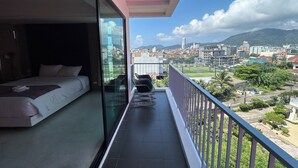 A balcony with a bed and a view of a cityscape and mountains. - Coco Boutique Hotel (Patong)