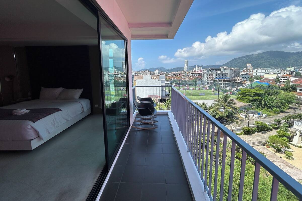 A balcony with a bed and a view of a cityscape and mountains.