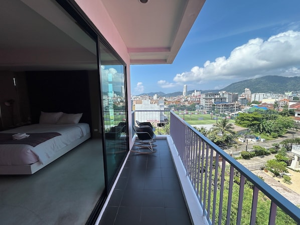 Un balcón con una cama y vistas a una ciudad y montañas.