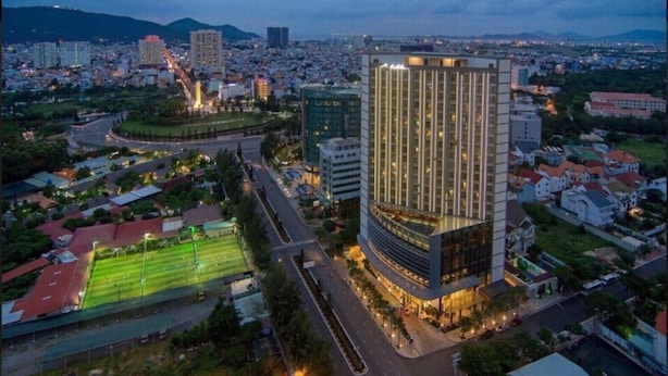 A high-rise hotel with a modern design, surrounded by a well-maintained urban area with roads and greenery. - The Grand Condotel (Ho Chi Minh City)