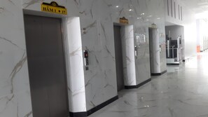 A corridor with marble walls and floors, featuring elevator doors labeled "HÀM 1" and "HÀM 2". - The Grand Condotel (Ho Chi Minh City)