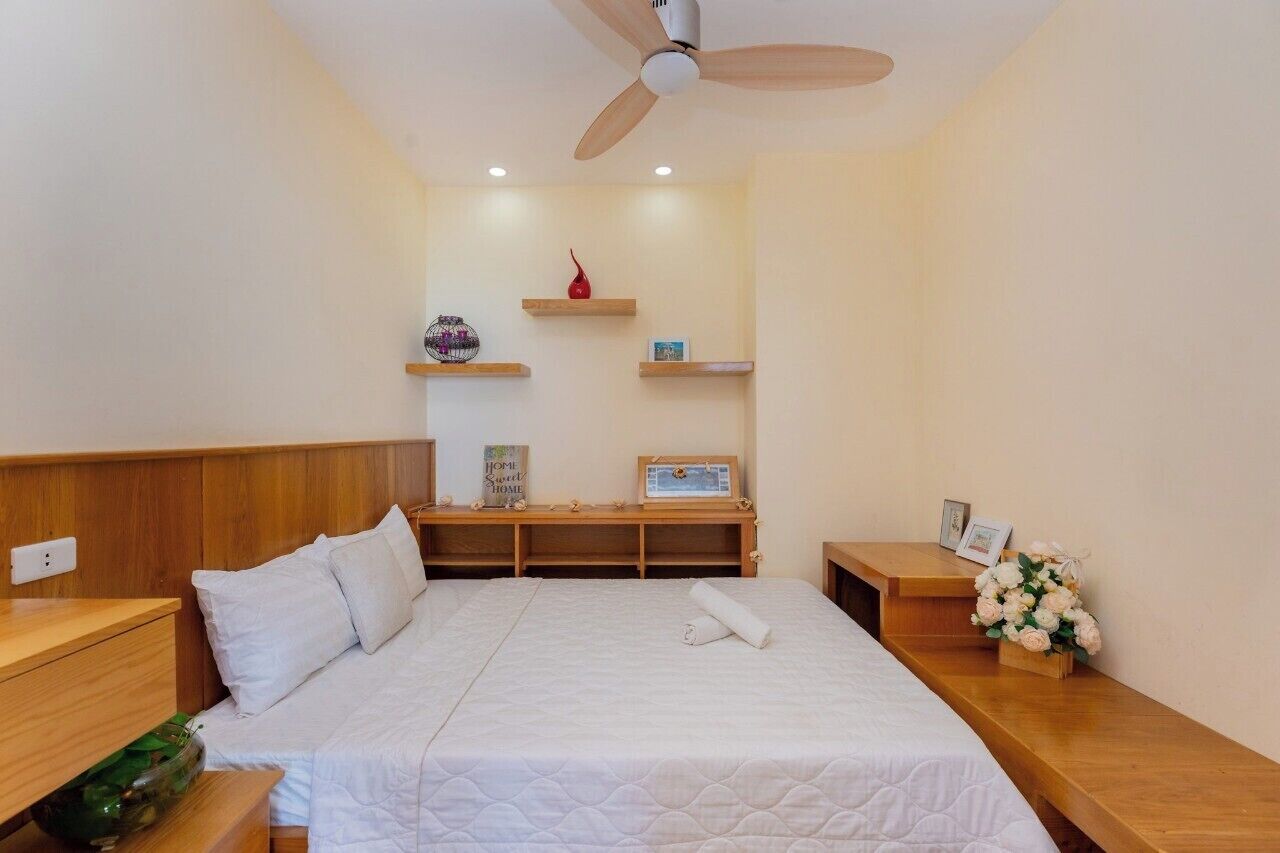 A neatly arranged bedroom with a bed, bedside tables, a wooden bench, and a ceiling fan.
