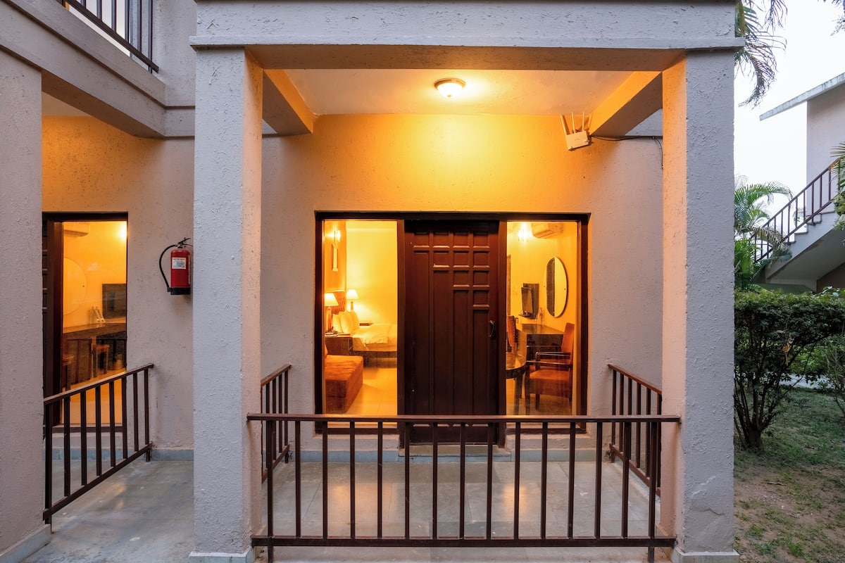 A hotel entrance with a wooden door, a small balcony, and a fire extinguisher mounted on the wall.