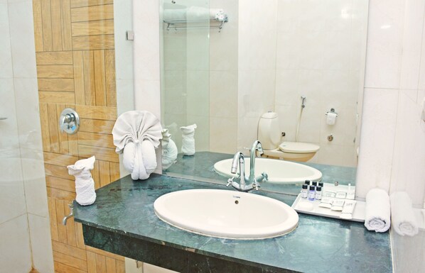 A bathroom with a large mirror, two sinks, a shower, and toiletries on the counter. - Click Resort Corbett, Tiger Den (Kaladhungi)