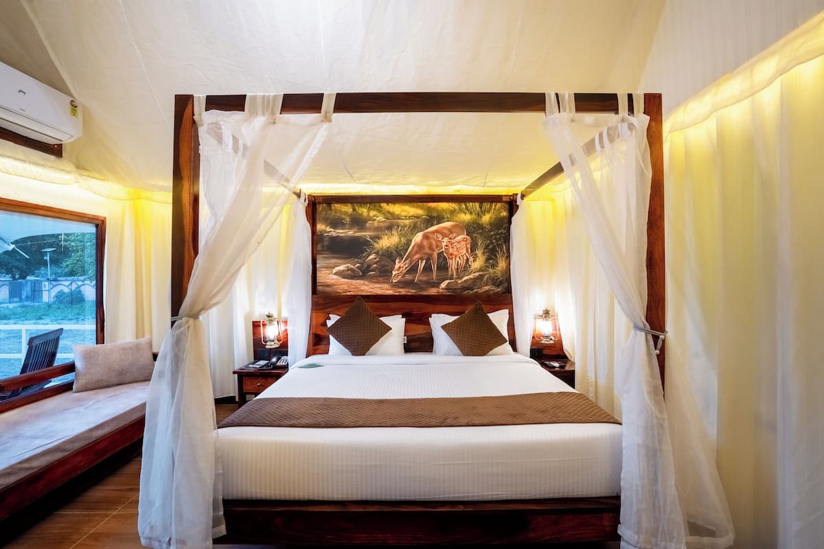 A large bed with a canopy, a painting of a deer, and a view of the outdoors.