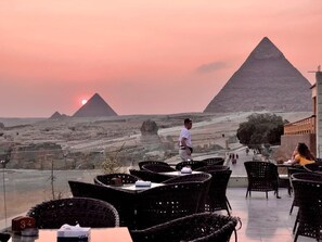 A restaurant with outdoor seating overlooking the pyramids.