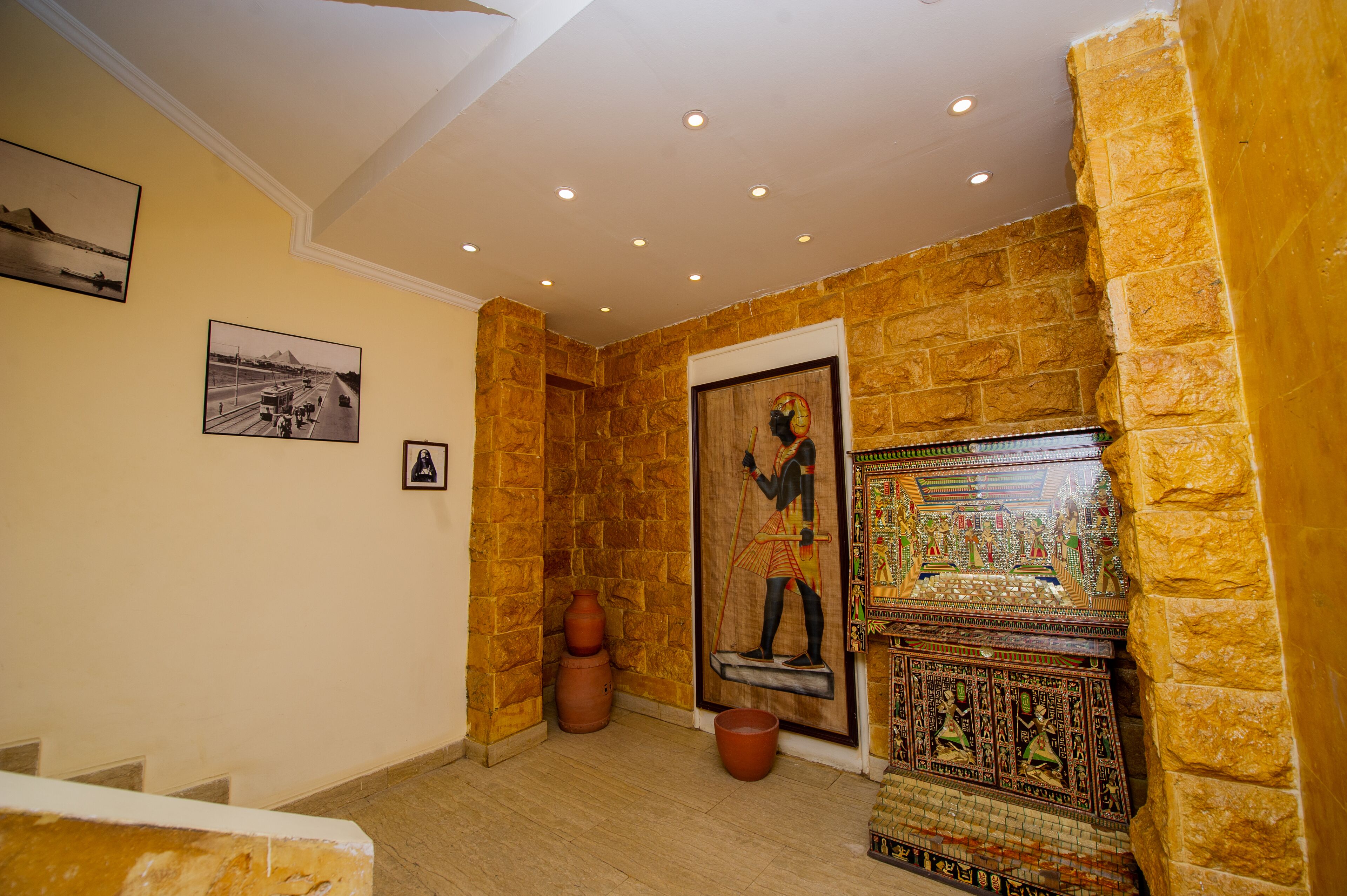 A hallway with stone walls, a door with a decorative panel, and a tiled wall with a mosaic.