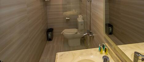 A bathroom with a large mirror, a sink with a chrome faucet, and a toilet.