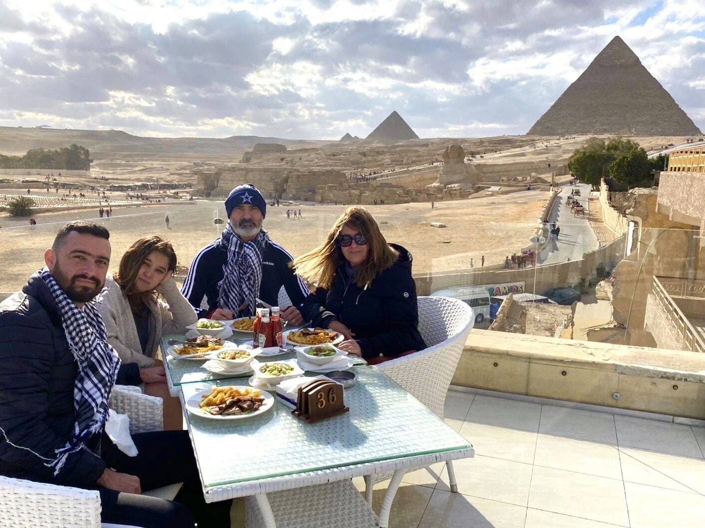A table with food and drinks, overlooking a pyramid and a desert landscape.